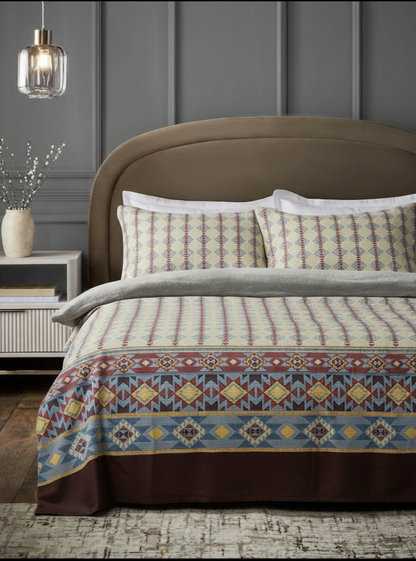 Bed with patterned bedding and pillows in a room with gray walls and a pendant light.