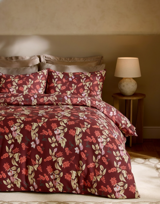 Floral patterned bedding set on a bed with a lamp in the background