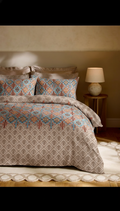 Bed with patterned bedding and pillows in a bedroom setting.