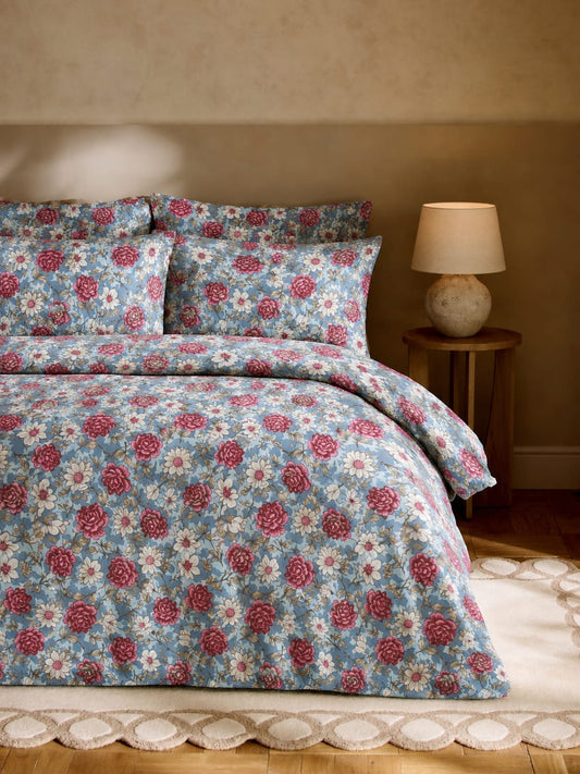 Floral bedding set on a bed with a lamp in the background