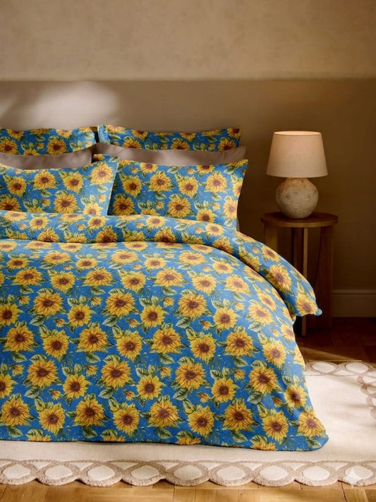 Sunflower patterned bedding set on a bed with a lamp in the background.