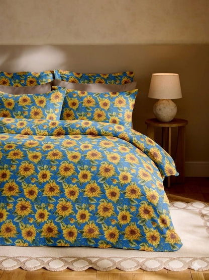 Sunflower patterned bedding set on a bed with a lamp in the background.