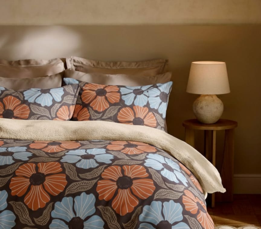 Floral patterned bedding set on a bed with a lamp in the background