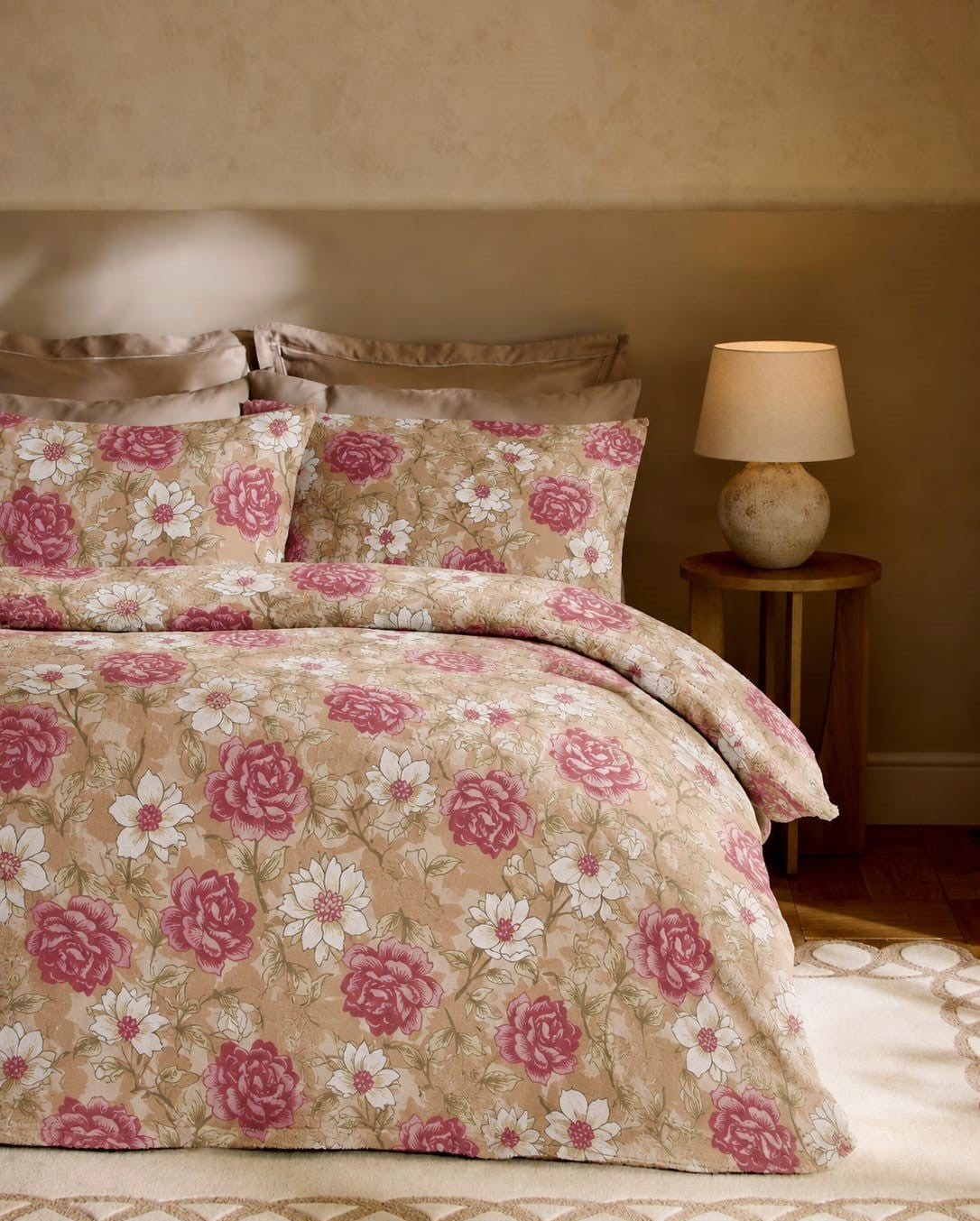 Floral patterned bedding set on a bed with a lamp in the background