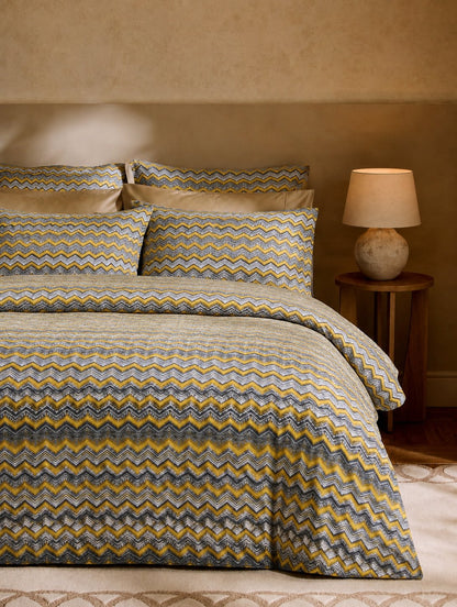 Bed with zigzag patterned bedding in a bedroom setting