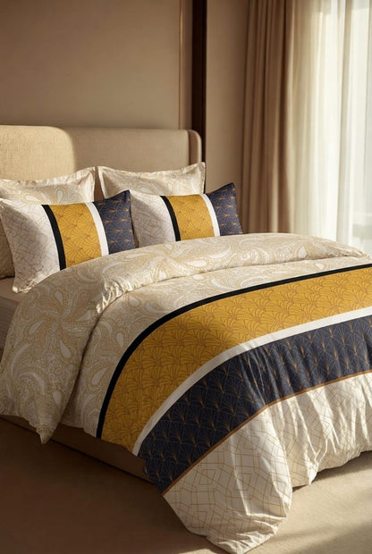 A styled bed dressed in a cream and gold patterned duvet cover with a wide gold and navy blue striped runner, matching striped pillow shams, and solid navy pillows, set in a warm-toned bedroom.