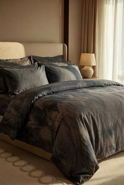 Neatly made bed with dark gray bedding in a bedroom setting.